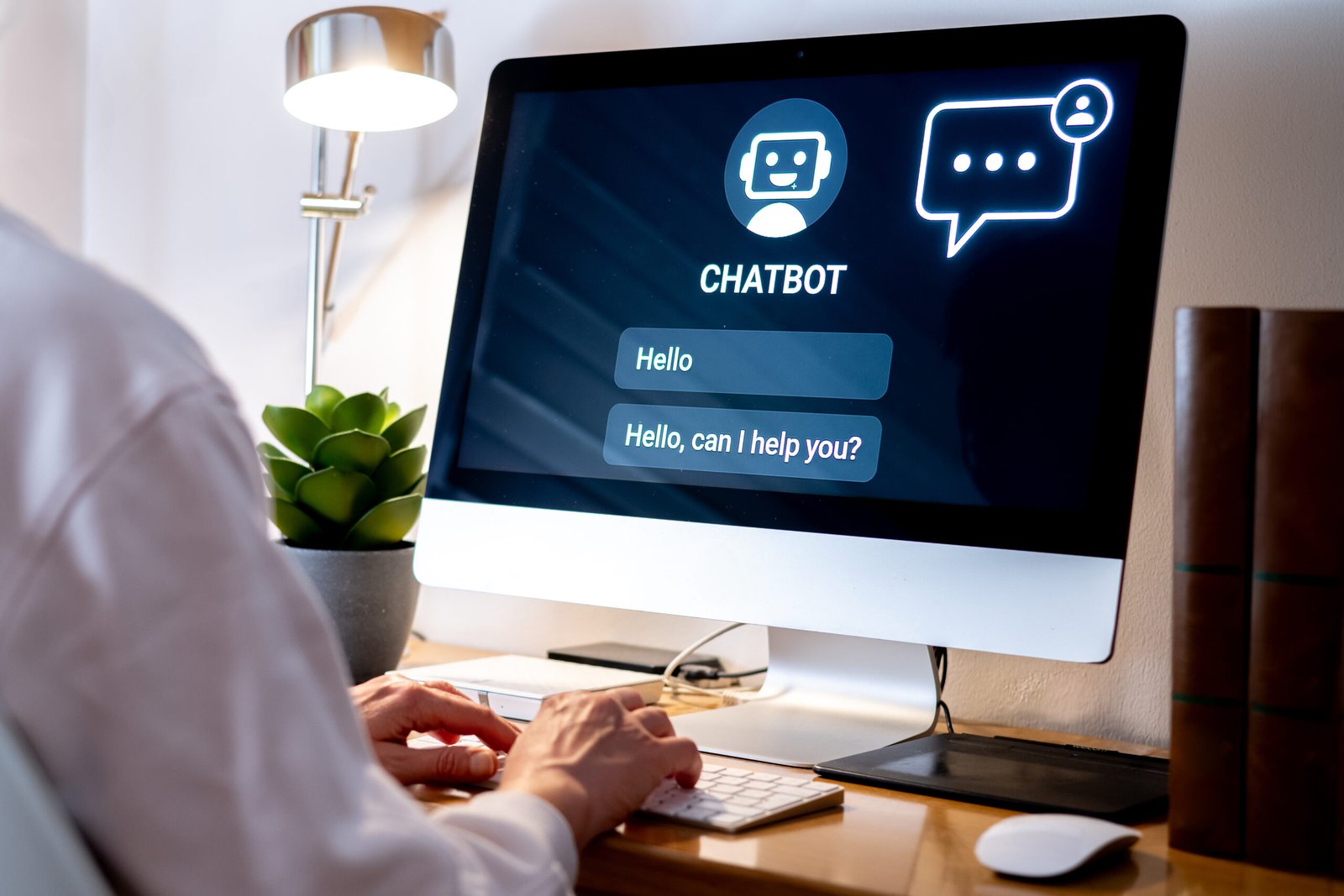 Office worker typing on a computer keyboard interacting with a chatbot on a computer screen, providing automated customer support using future technology